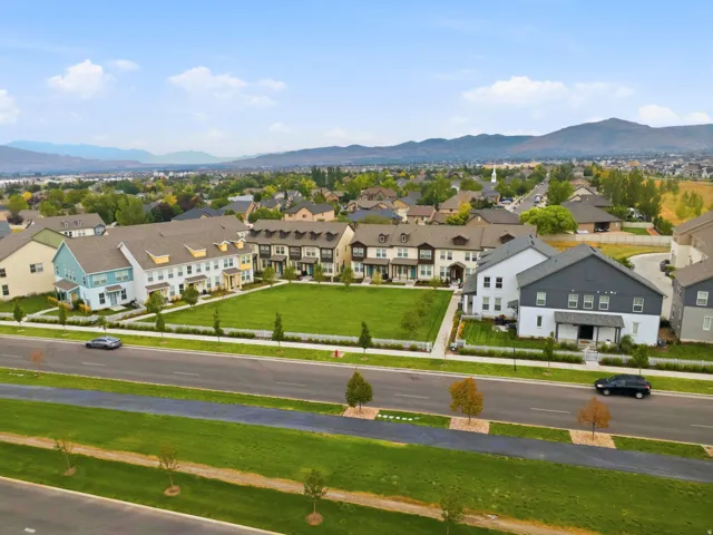 Community with townhomes and detached residences, green spaces, and mountain scenery