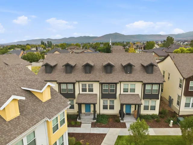 Townhome exterior featuring dormer windows, covered front entrance, and contrasting trim