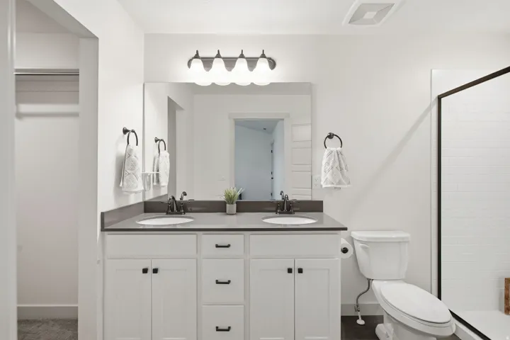 Dual vanity with undermount sinks, dark countertops, and white shaker-style cabinetry