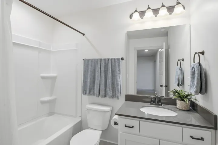 White vanity with dark countertop, an undermount sink, and a framed mirror