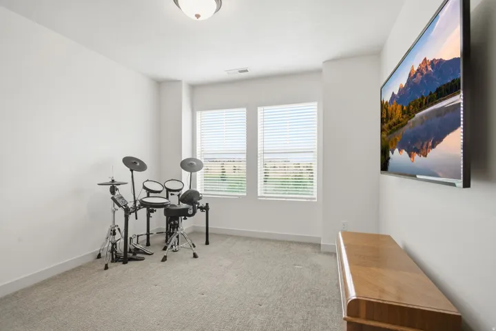 Recessed lighting illuminates a room featuring two windows with horizontal blinds, carpeted flooring, and white painted walls