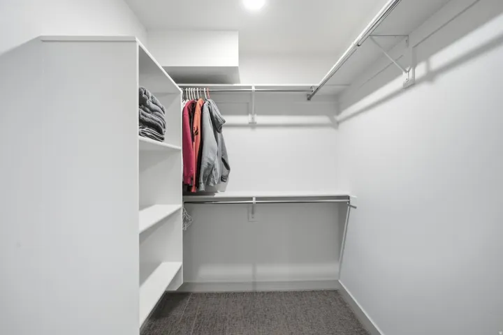Walk-in closet featuring built-in shelving, multiple hanging rods, and recessed lighting