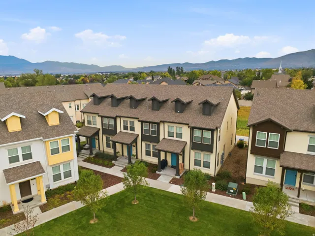 Townhome community featuring multi-level residences with contrasting facade colors, covered entryways, and dormer windows