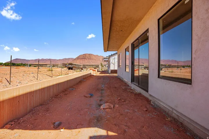 Exterior featuring stucco siding, large fixed windows, sliding glass door, and an extended eave