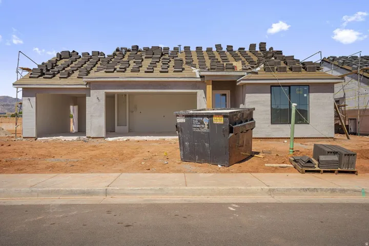 New construction with a two-car garage, stucco exterior, and a partially installed tile roof