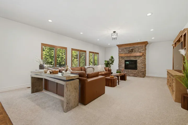 Stone-clad fireplace with wood mantel, recessed lighting, and a multi-pane window array