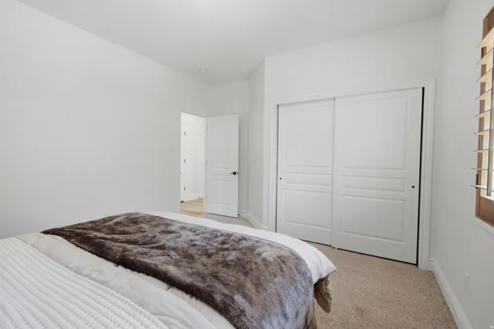Neutral tone wall finishes, recessed ceiling lighting, carpeted flooring, sliding panel closet doors, and window with wood-finish shutters