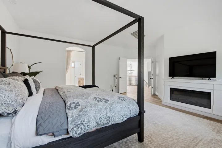 White walls with arched doorway entry, wide plank wood-finish flooring, and a built-in electric fireplace