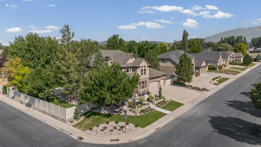 Corner lot property featuring a stone and brick exterior, a two-car garage, established landscaping, and a fenced side yard