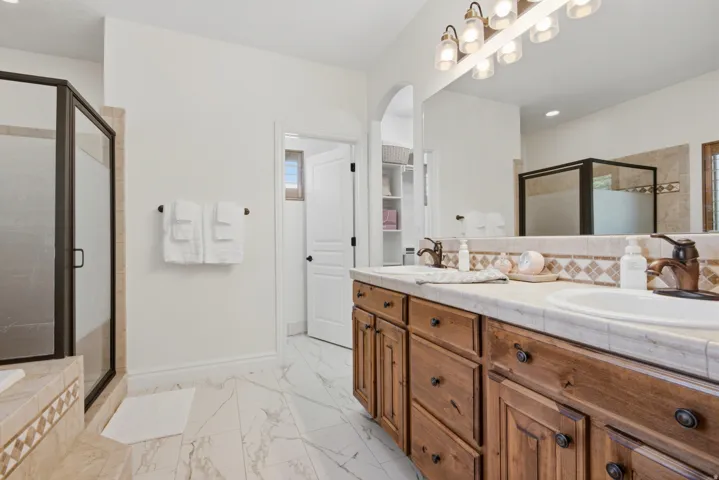 Dual vanity with integrated sinks, wood-finish cabinetry, and a full-width mirror