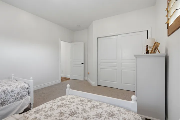 White paneled sliding closet doors, light neutral carpeting, and white painted walls