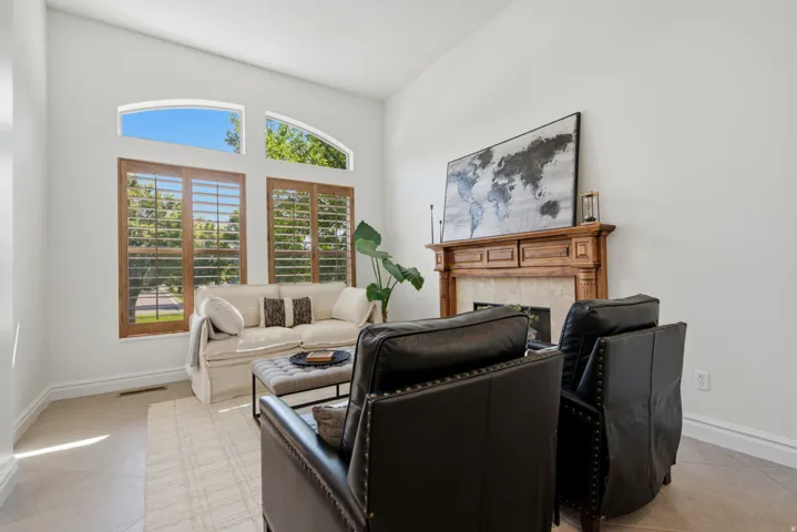 Vaulted ceiling, arched transom windows, wood-finish window shutters, wood-finish fireplace mantel, and tile flooring