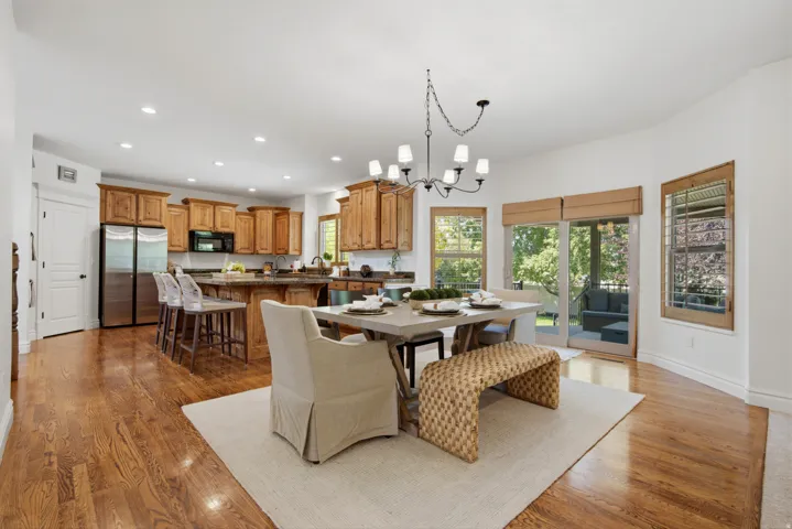 Hardwood flooring throughout, kitchen with wood cabinetry and stainless steel appliances, dining area with chandelier, sliding glass door to exterior, and recessed lighting