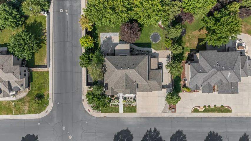 Expansive lot with mature trees, paved driveways, a multi-gabled roof, and landscaped front yard