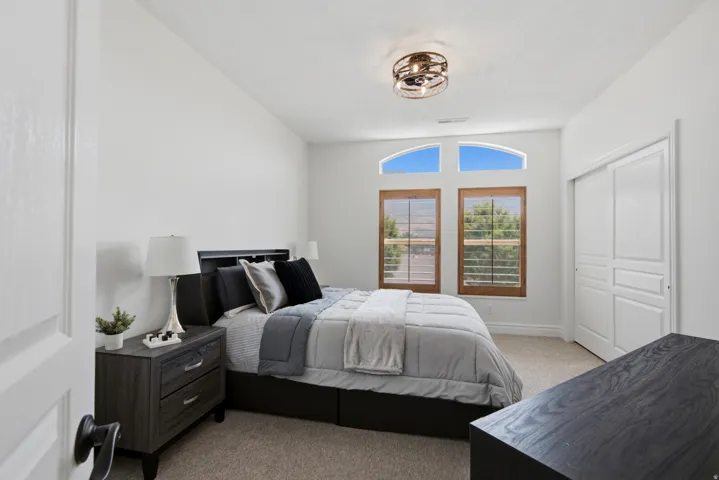 Arch-top clerestory windows, wood-framed windows, vaulted ceiling, flush mount ceiling light fixture, and sliding panel closet doors