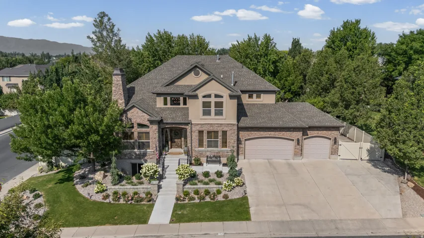 Stone and stucco exterior with multiple gables, a covered entry, an attached two-car garage, and a concrete driveway
