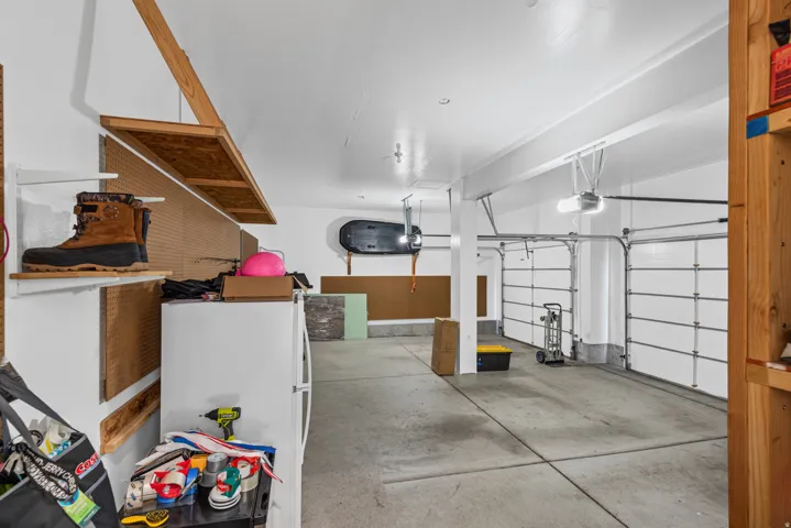 Concrete flooring with two garage doors and overhead storage shelving