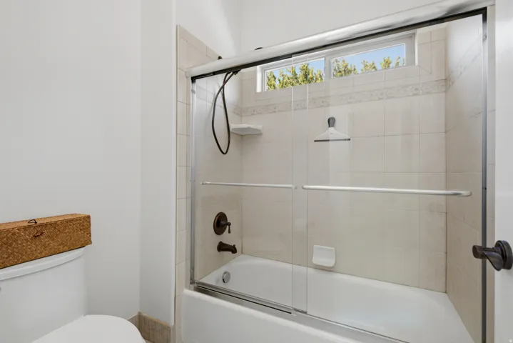 Bathtub with tiled surround, glass shower enclosure, and a transom window