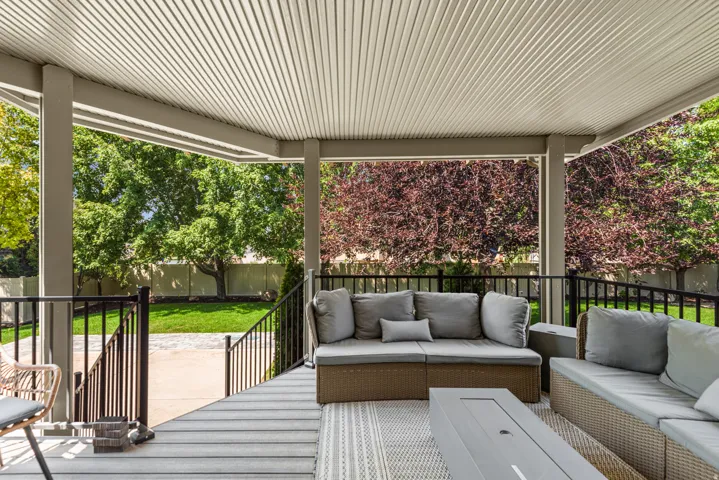 Covered patio featuring a slatted ceiling, wood-finish flooring, and black metal railings