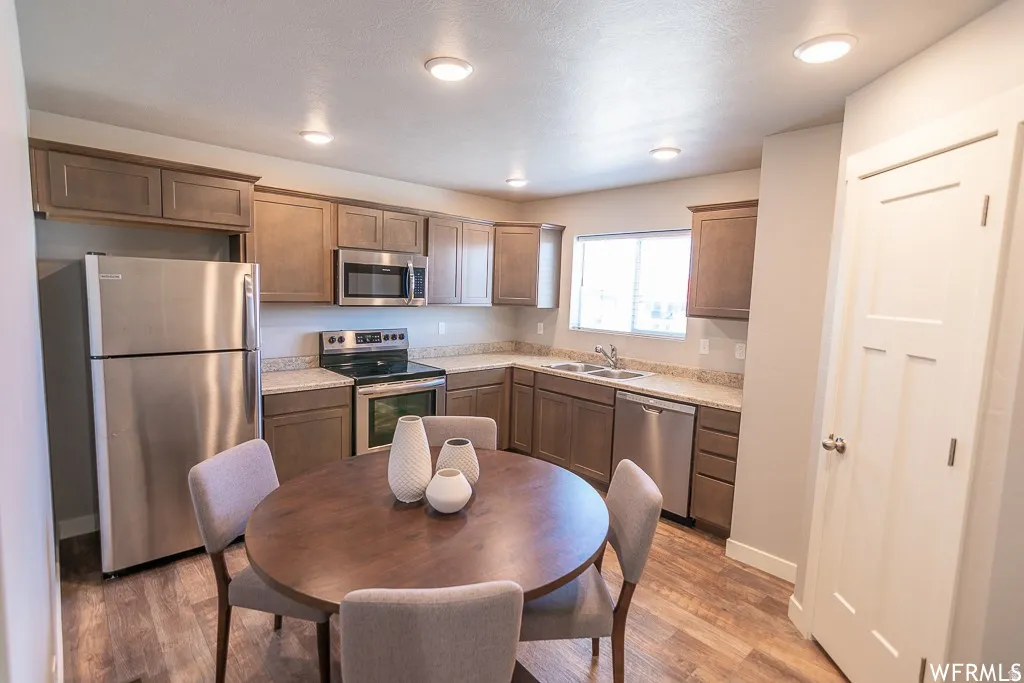 Kitchen featuring wood-finish flooring, recessed lighting, stainless steel appliances, and a window with blinds