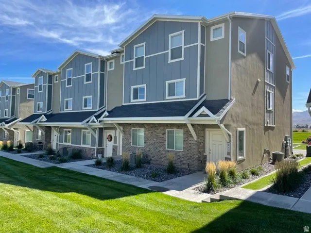 Multi-level townhome exterior featuring contemporary siding, brick accents, white trim, and a gabled roofline