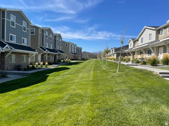 Row of townhomes featuring varied siding and brick exteriors, concrete walkways, and landscaped entryways