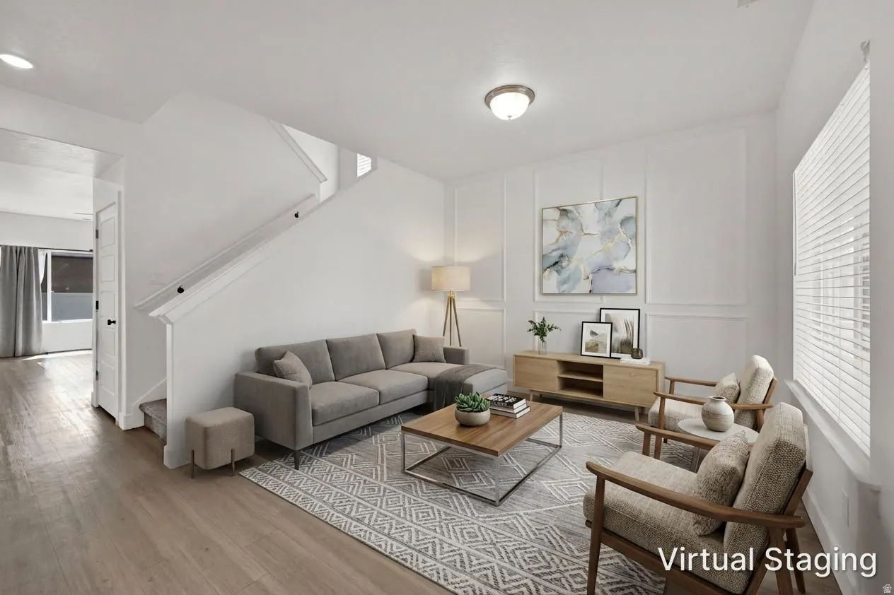 Wood-finish flooring, staircase with white railing, built-in wall paneling, and an overhead flush-mount light fixture