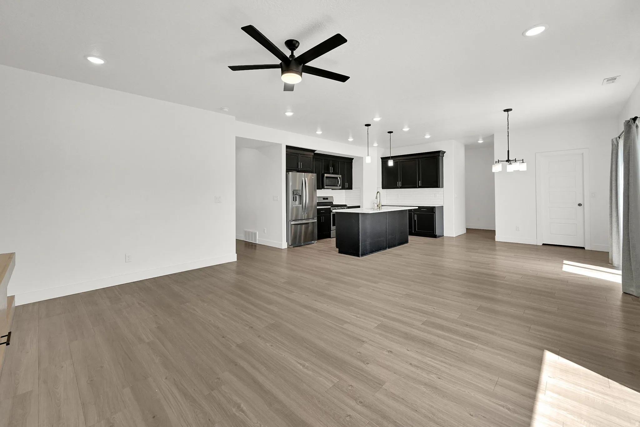 Open-concept living area featuring wood-finish flooring, recessed lighting, and a contemporary ceiling fan