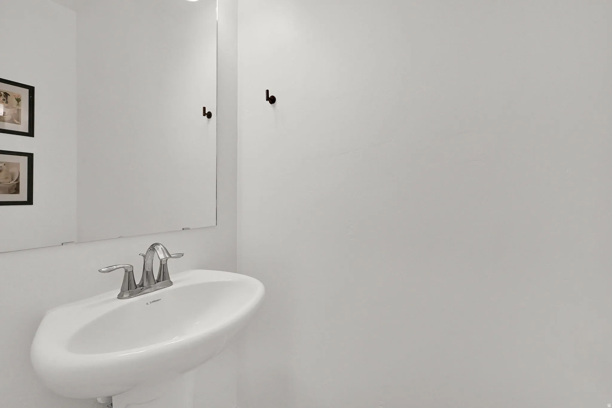 Pedestal sink with chrome-finish faucet and wall-mounted mirror