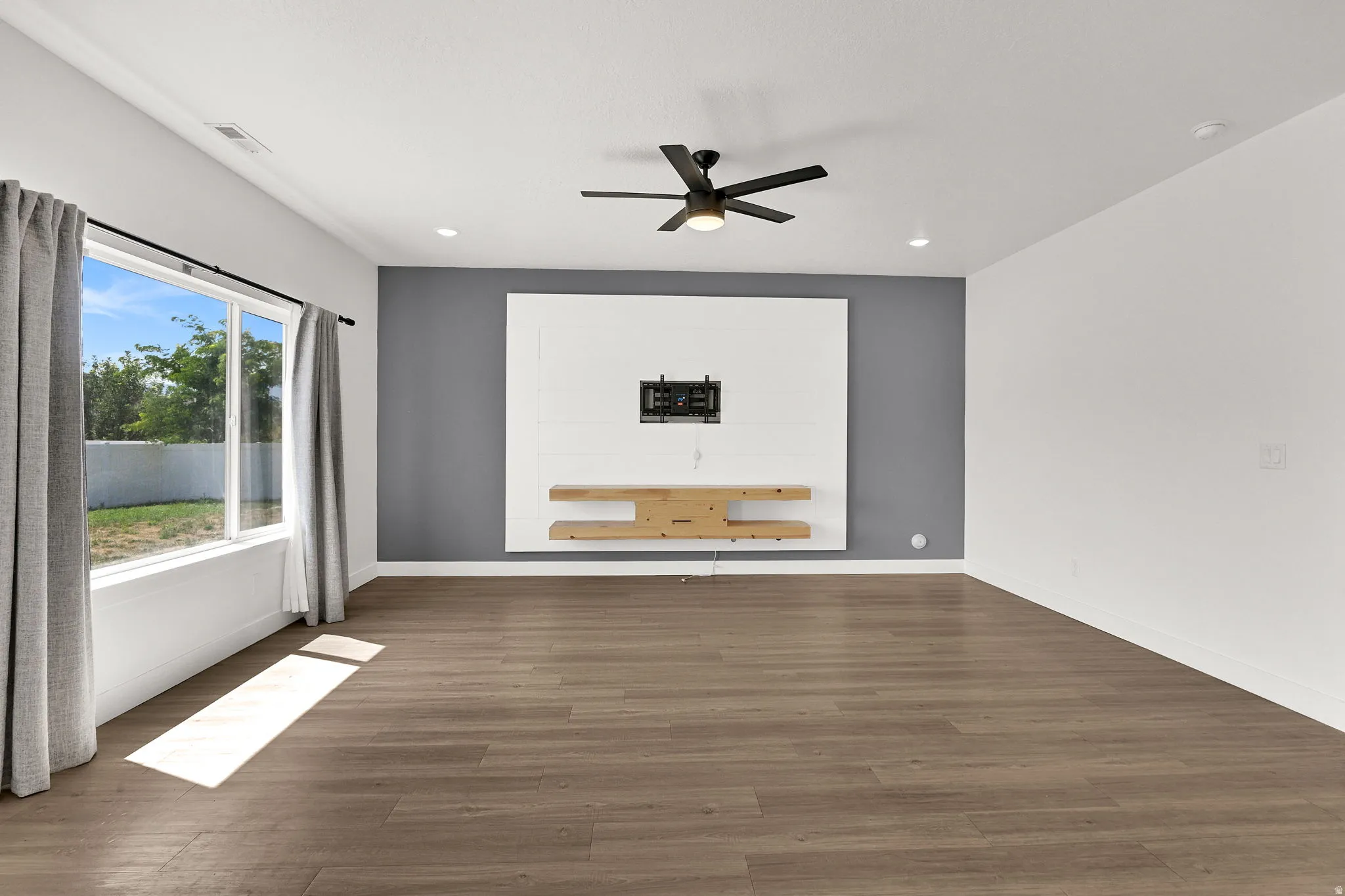Wide plank wood-finish flooring, recessed lighting, and a modern ceiling fan with light fixture
