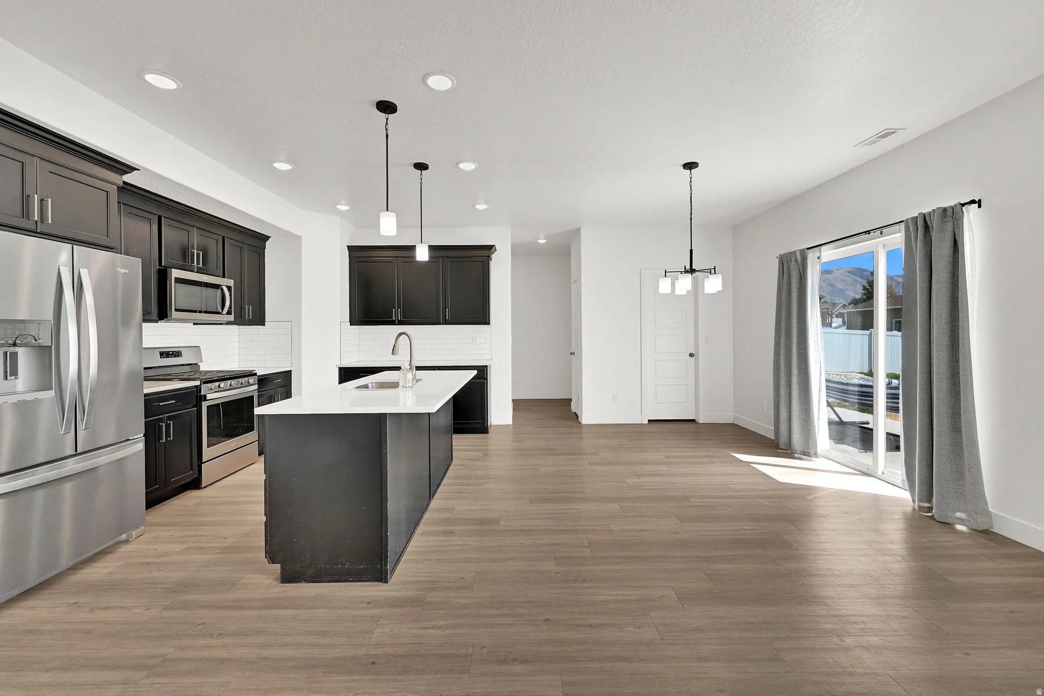Kitchen with dark cabinetry, stainless steel appliances, and a central island with a white countertop