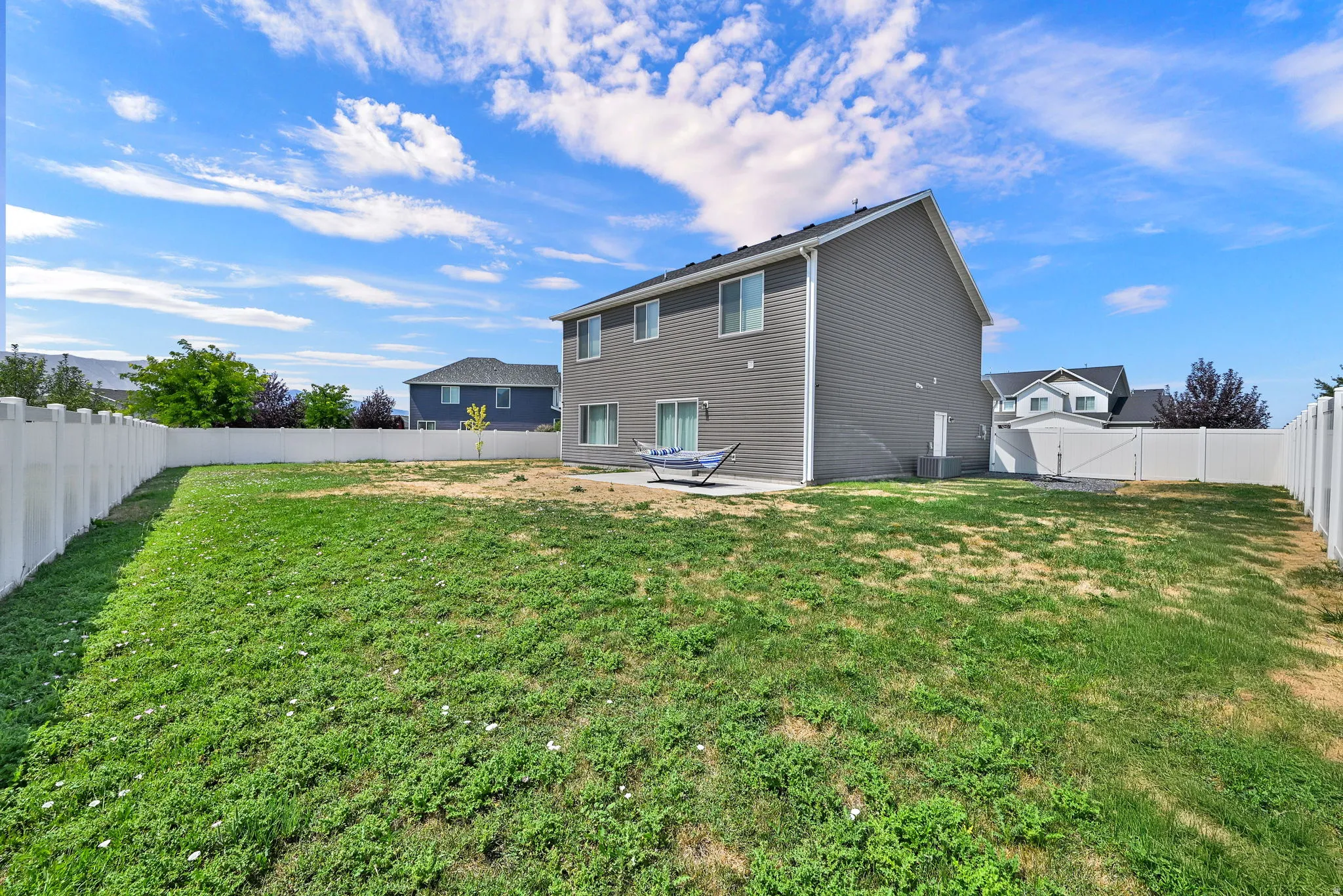 Fenced backyard featuring a gravel patio and a two-story residence with siding