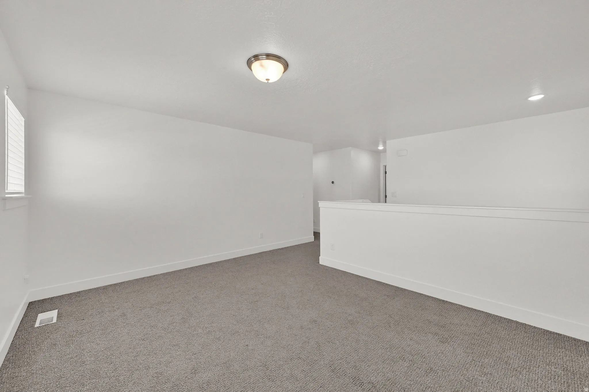 Recessed lighting, flush mount lighting, textured carpeting, white walls, and white trim