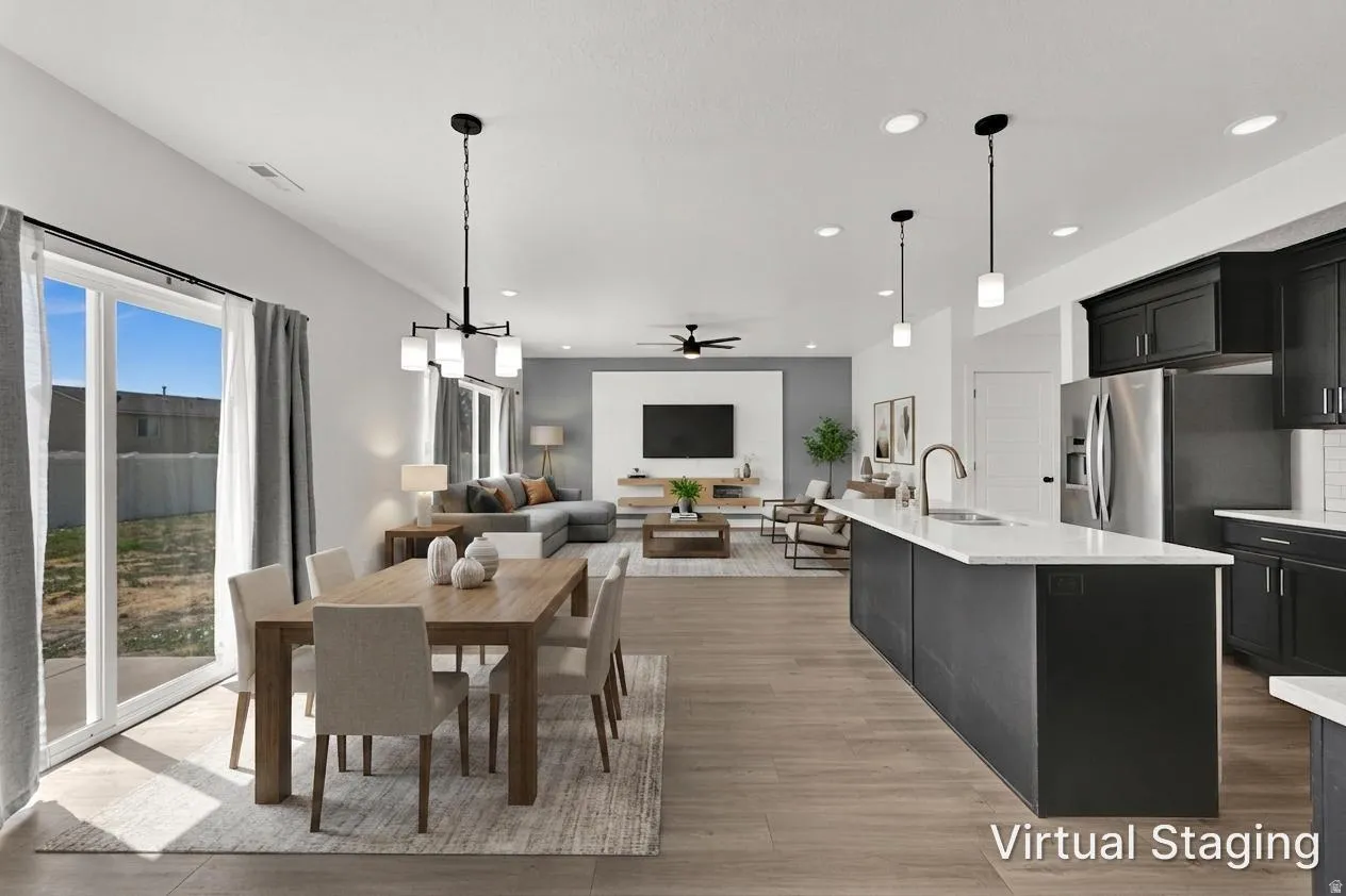 Open-concept living area with wood-finish flooring, a kitchen island, pendant lighting, and sliding glass doors