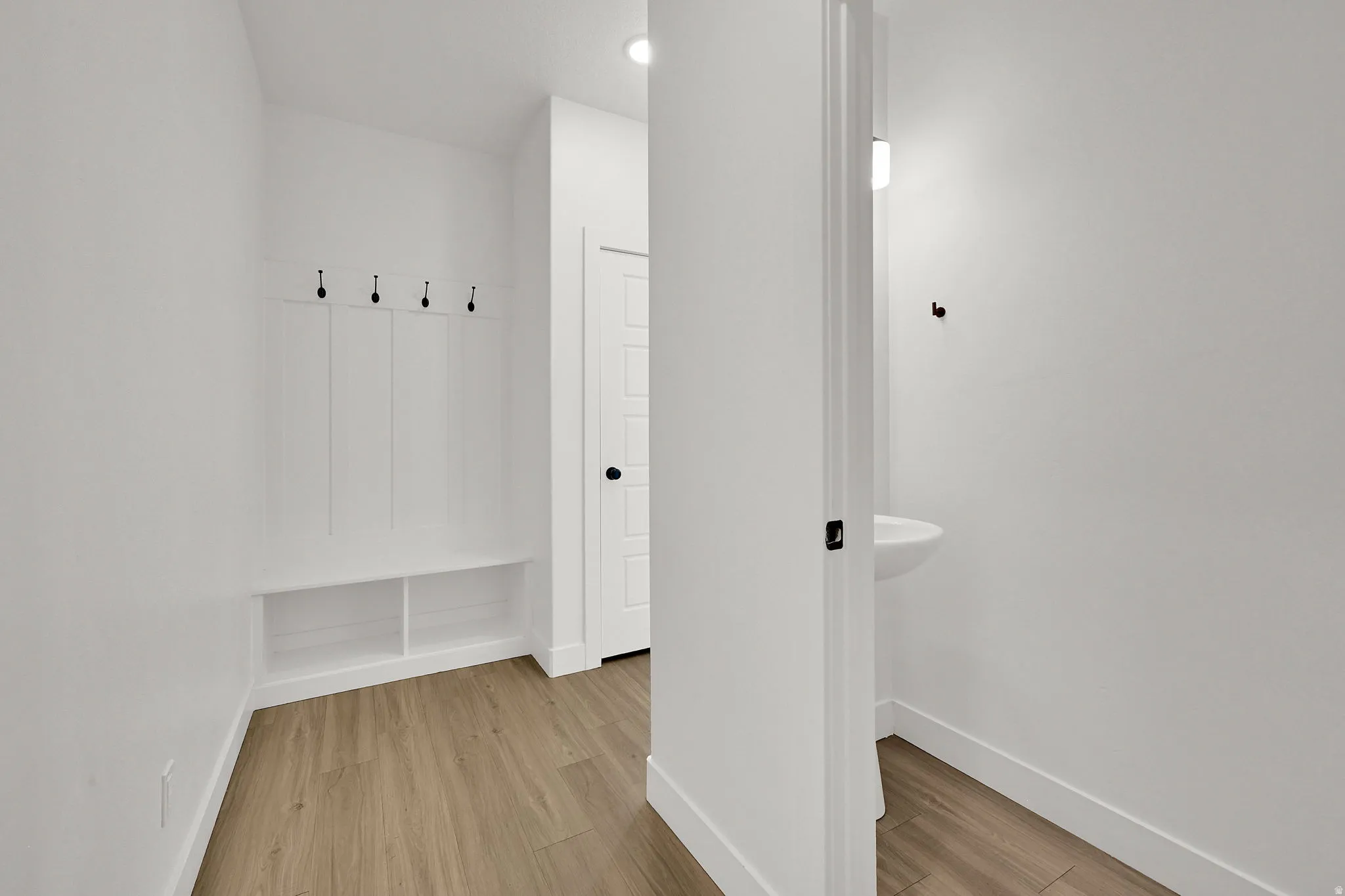 Built-in coat rack with bench seating, dedicated storage cubbies, and wood-finish flooring
