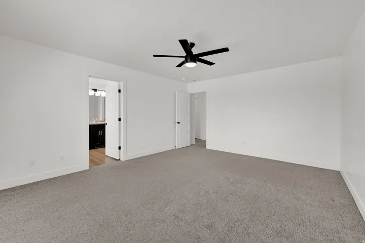 White walls with gray carpeting, featuring a matte black ceiling fan