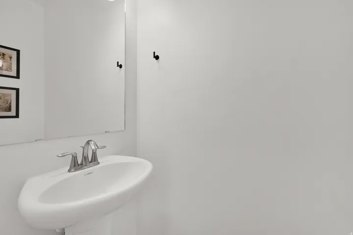 Pedestal sink with chrome-finish faucet and wall-mounted mirror