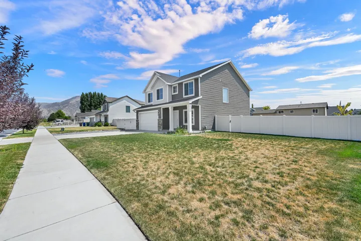 Two-story residence featuring a two-car garage, gray siding, white trim, and a white privacy fence