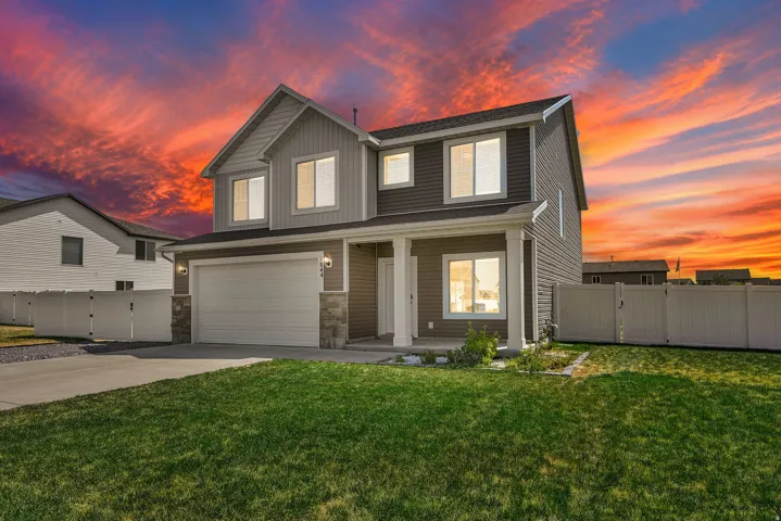Two-story exterior with a covered porch entry, attached garage, and stone accents