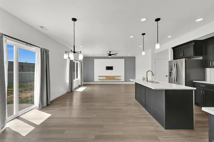 Open-concept living space featuring wood-finish flooring, a kitchen island with a white countertop, dark cabinetry, and stainless steel appliances