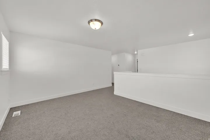Recessed lighting, flush mount lighting, textured carpeting, white walls, and white trim