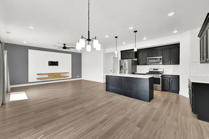 Open-concept living space featuring wood-finish flooring, a modern black chandelier, and recessed lighting
