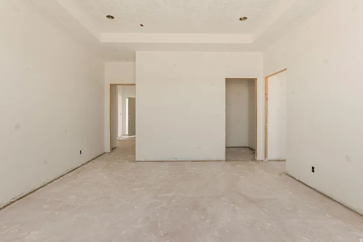 Recessed lighting fixtures, tray ceiling, unpainted drywall, and exposed door frames