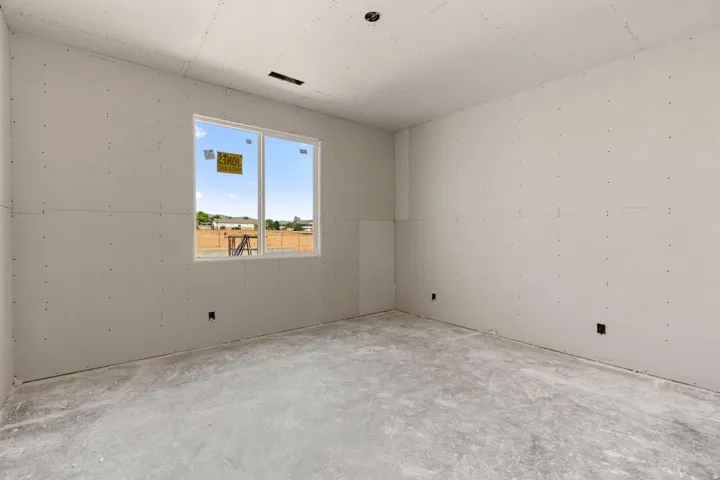 Bright, open bedroom featuring drywall construction with recessed ceiling lighting, large dual-pane window with natural light exposure, and concrete flooring throughout