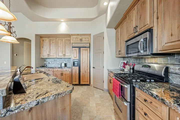 Kitchen featuring wood-finish cabinetry, granite countertops, stainless steel appliances, and tile flooring