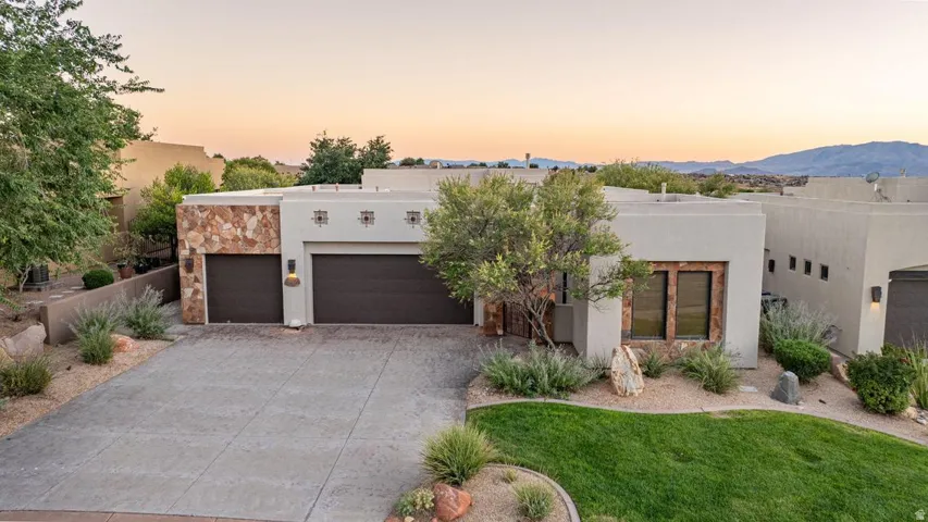 Stucco exterior with stone accents, integrated two-car garage, and landscaped front yard
