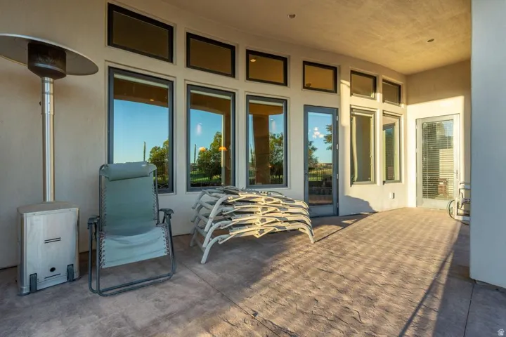 Covered patio featuring a concrete stamped floor, multiple large windows, and a glass-paneled door