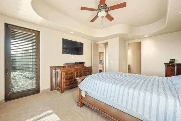 Cove ceiling with recessed lighting, ceiling fan, carpeted flooring, and glass-paneled exterior door