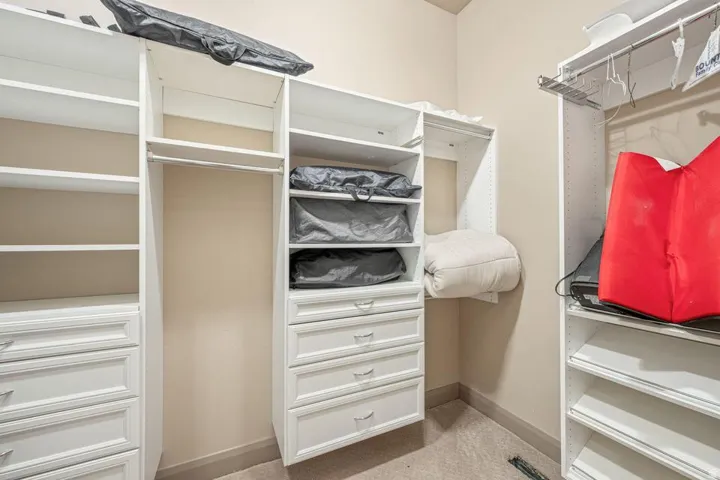 Built-in white cabinetry with multiple shelving units, integrated drawers, and garment hanging rods