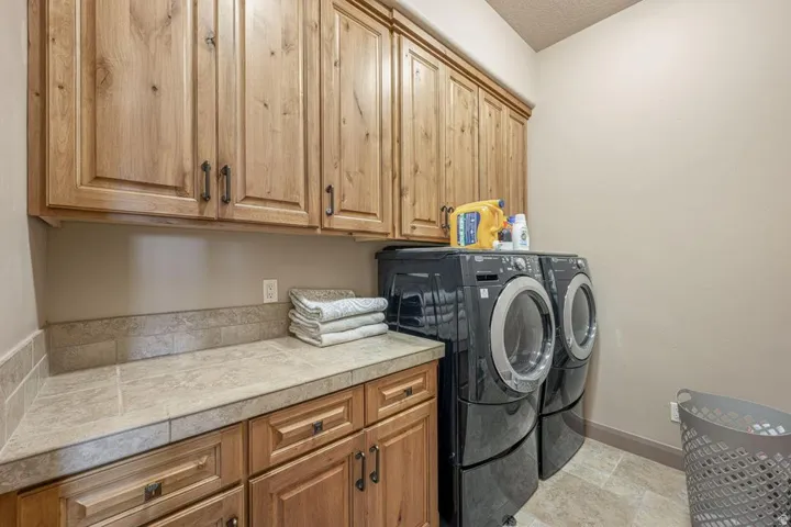 Wood-finish cabinetry, tile flooring, built-in countertop, and a tiled backsplash